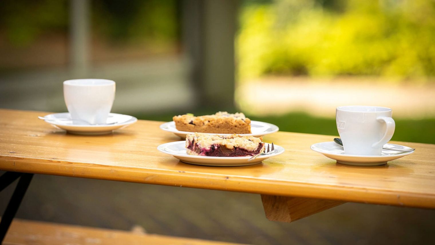 Kuchen und Kaffee auf einem Holztisch im Sommer draußen vor dem Museumscafé der Camera Obscura Mülheim