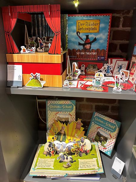 Optische Spiele von Räuber Hotzenplotz und Shaun, das Schaf stehen aufgebaut in einem Regal im Museusshop der Camera Obscura.
